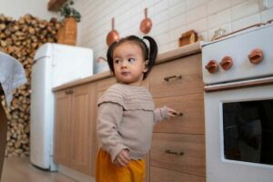 Criança na cozinha com a mão no puxador de uma gaveta. Representação de Como evitar acidentes em casa