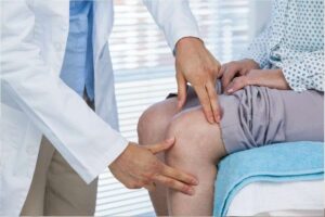 Close de ortopedista examinando o joelho de um paciente. Representação de como tratar lesões no joelho.