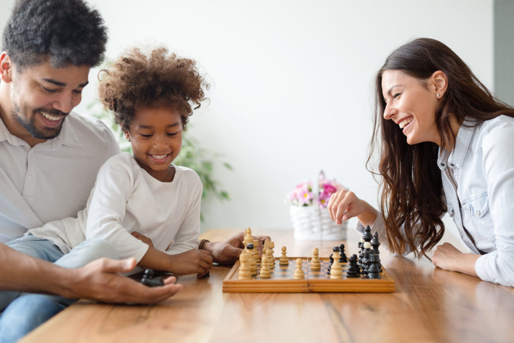 Família feliz jogando xadrez para cultivar a saúde emocional infantil