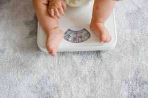 Detalhe de criança sentado em uma balança. Representação da obesidade infantil e sobrepeso.