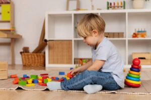 Menino com autismo brincando com blocos de montar em um quarto. Representação do autismo em criança.